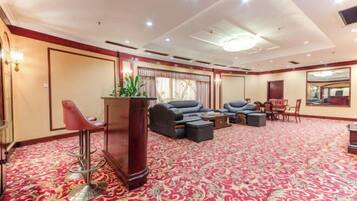 A spacious room with a red carpet, a bar area with stools, a sofa set, and a large mirror.