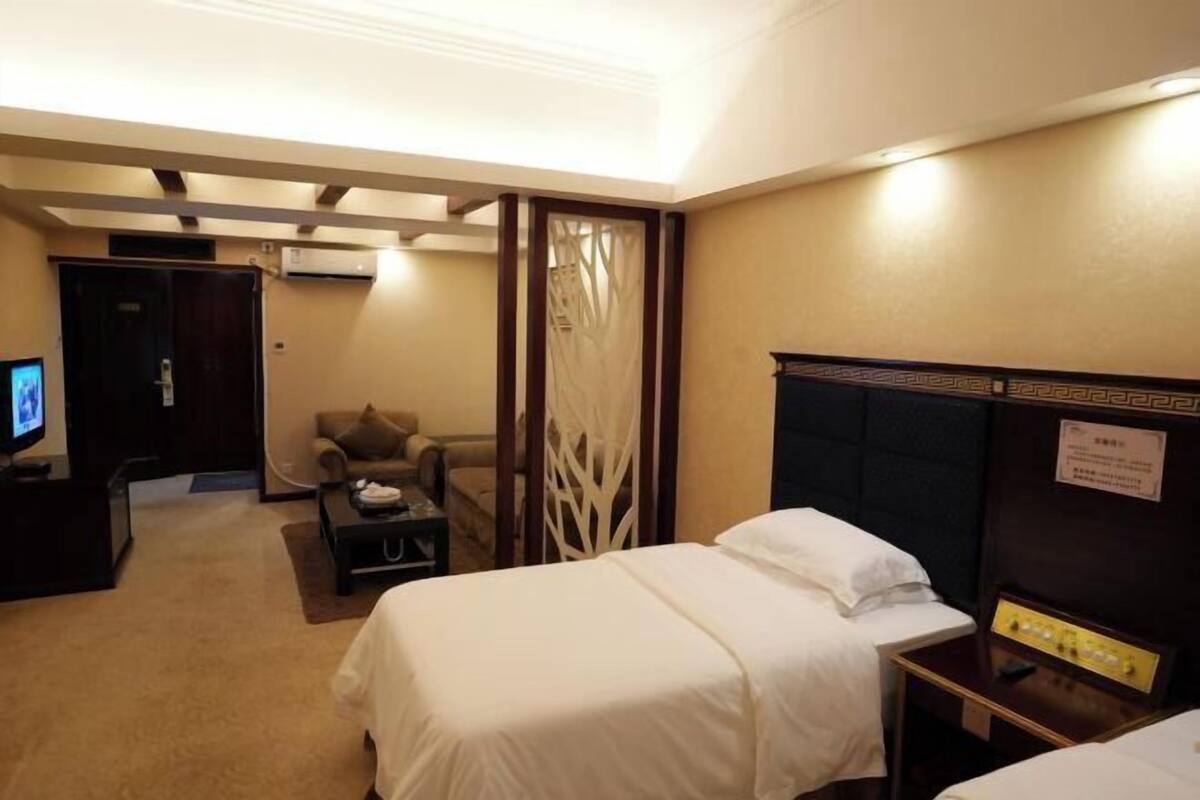 Una habitación de hotel con dos camas, televisión, escritorio y una silla.
