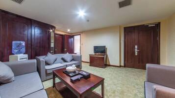 Uma sala de estar com sofá, mesa de centro, televisão e armários de madeira.