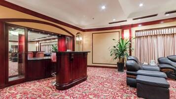 A hotel lobby with a reception desk, seating area, and a large potted plant.