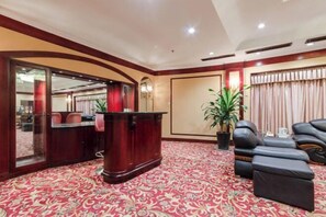 Un vestíbulo de hotel con una recepción, zona de estar y una planta grande en maceta.