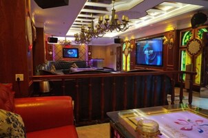 Área de bar com televisão, assentos e um candelabro.