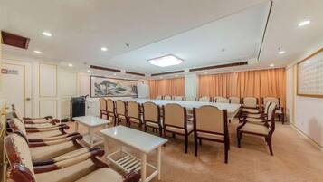 A conference room with a long table, chairs, and a carpeted floor.