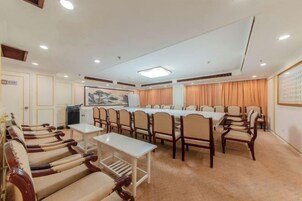 Un salón de conferencias con una mesa larga, sillas y piso alfombrado.