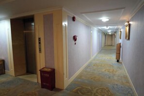 A hotel corridor with an elevator, a fire alarm, and a trash bin. - Temeisi Hotel (Jieyang)