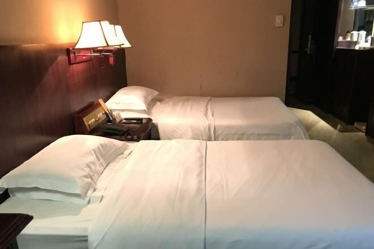Habitación de hotel con dos camas, una mesita de noche y una lámpara.