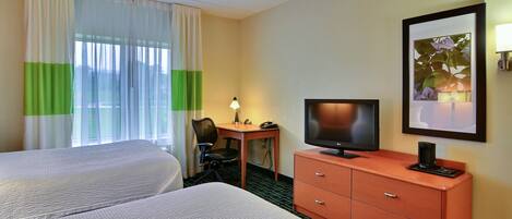 Habitación de hotel con dos camas, un escritorio con silla, televisor, cómoda y un cuadro en la pared.