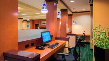 A hotel reception area with a wooden desk, computer, and chair.
