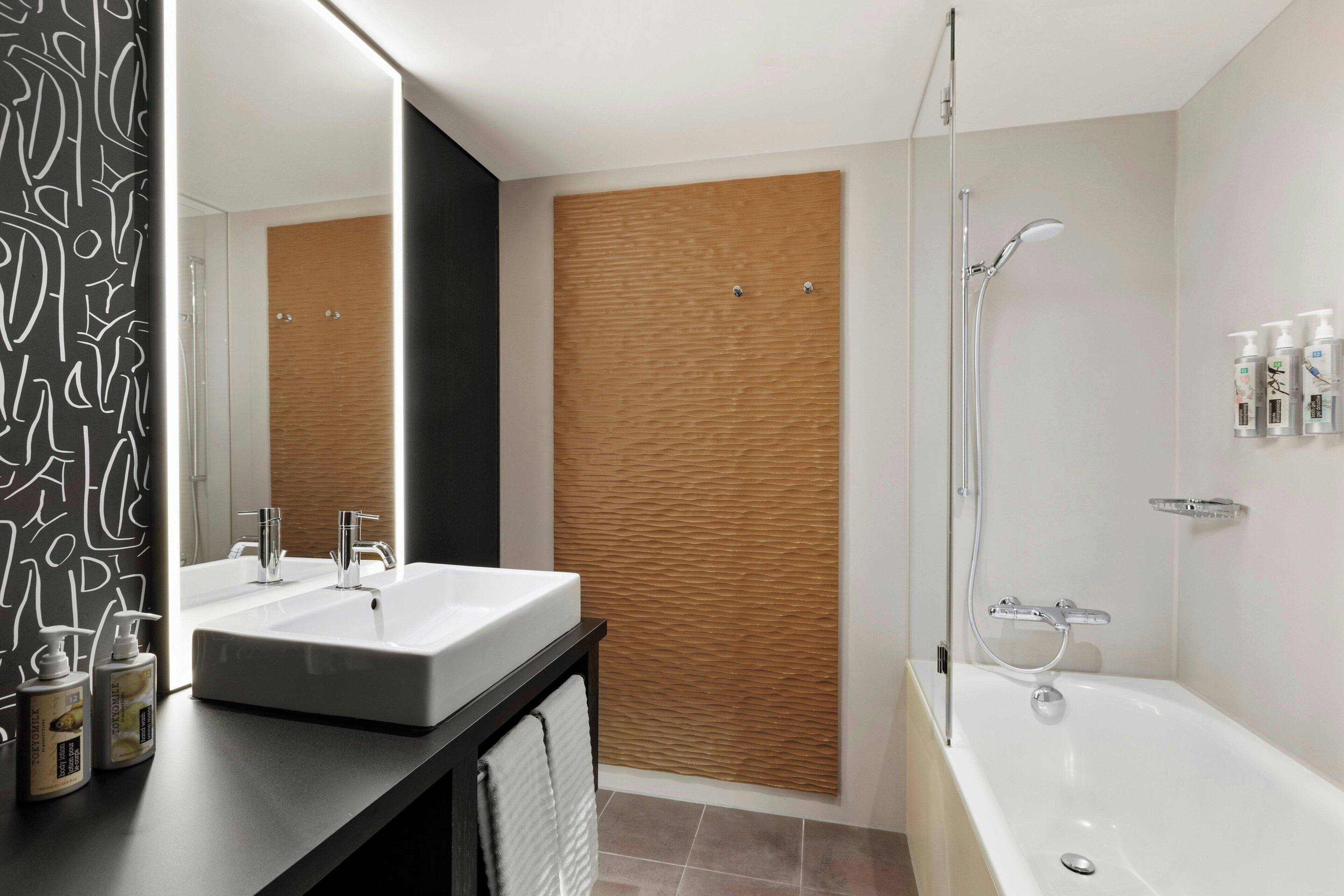 Un baño moderno con dos lavamanos, ducha y un espejo grande.