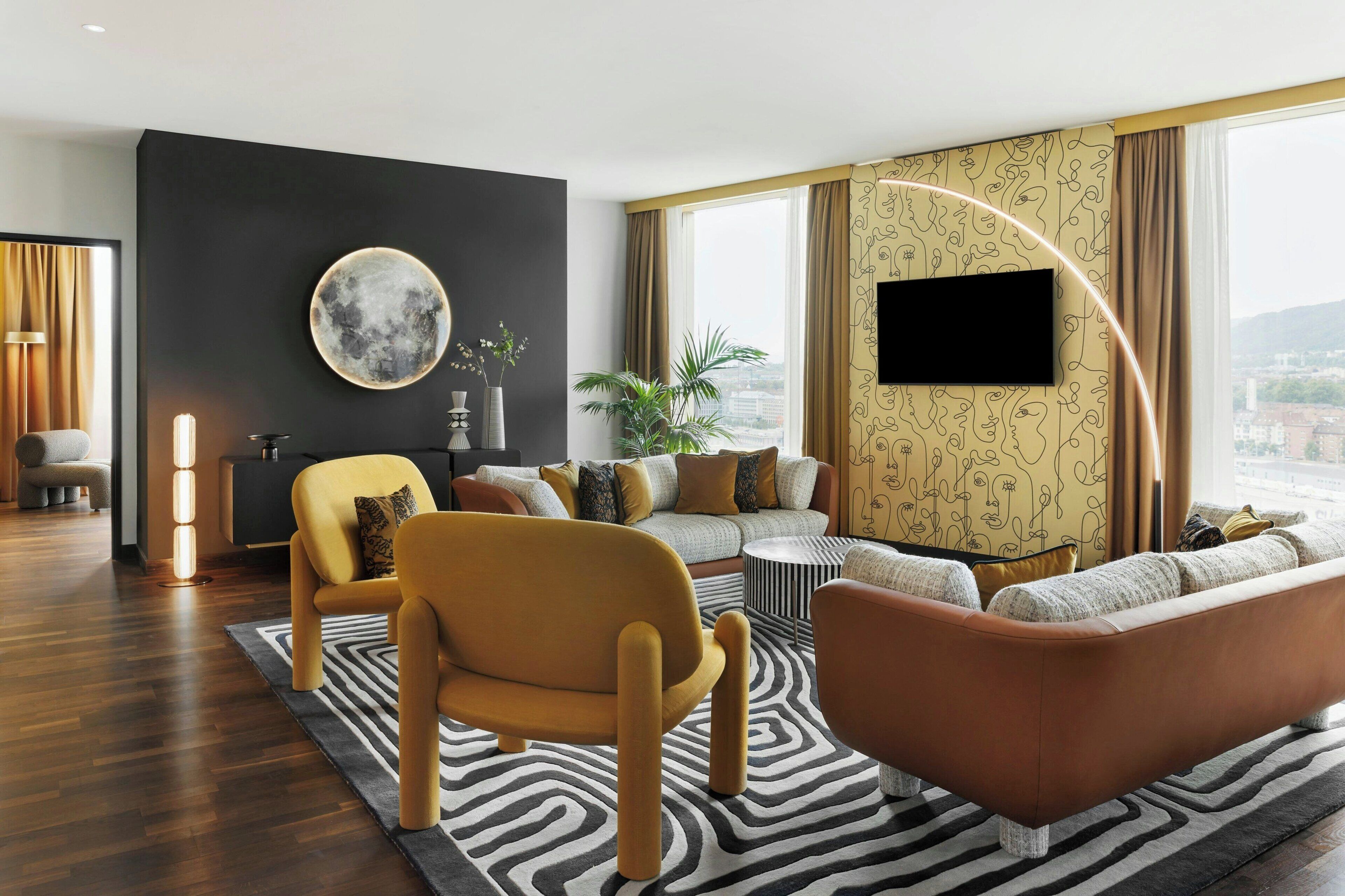 Una sala de estar moderna con un sofá, sillones, una mesa de centro y un amplio ventanal con cortinas.