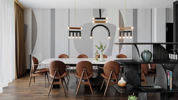 A modern dining area with a round table, brown chairs, and pendant lighting.