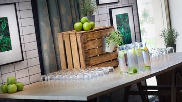 A table with green apples, a wooden crate, and clear glasses.