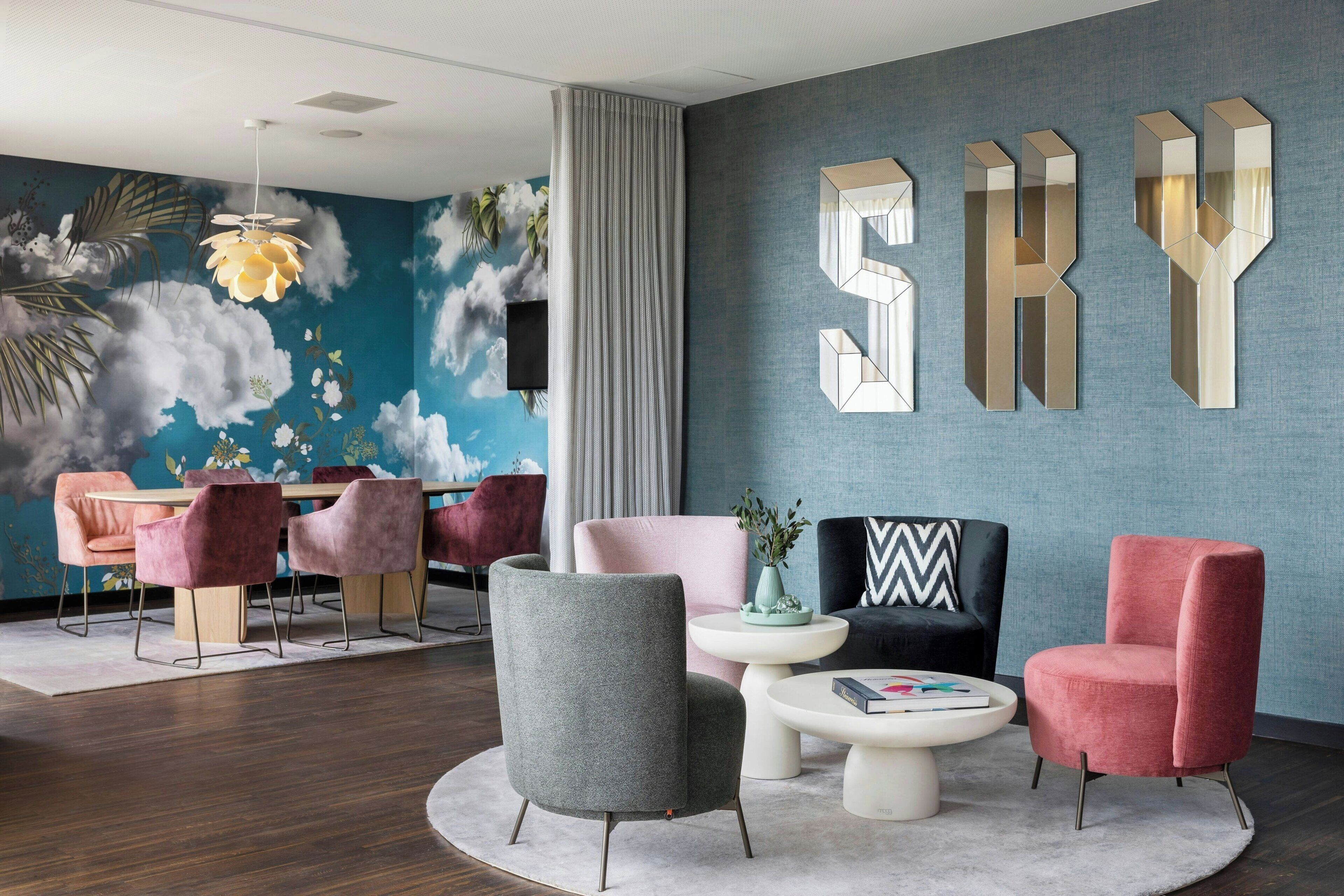 Un intérieur moderne comprenant un coin repas, un fauteuil gris, un fauteuil rose et une table basse.