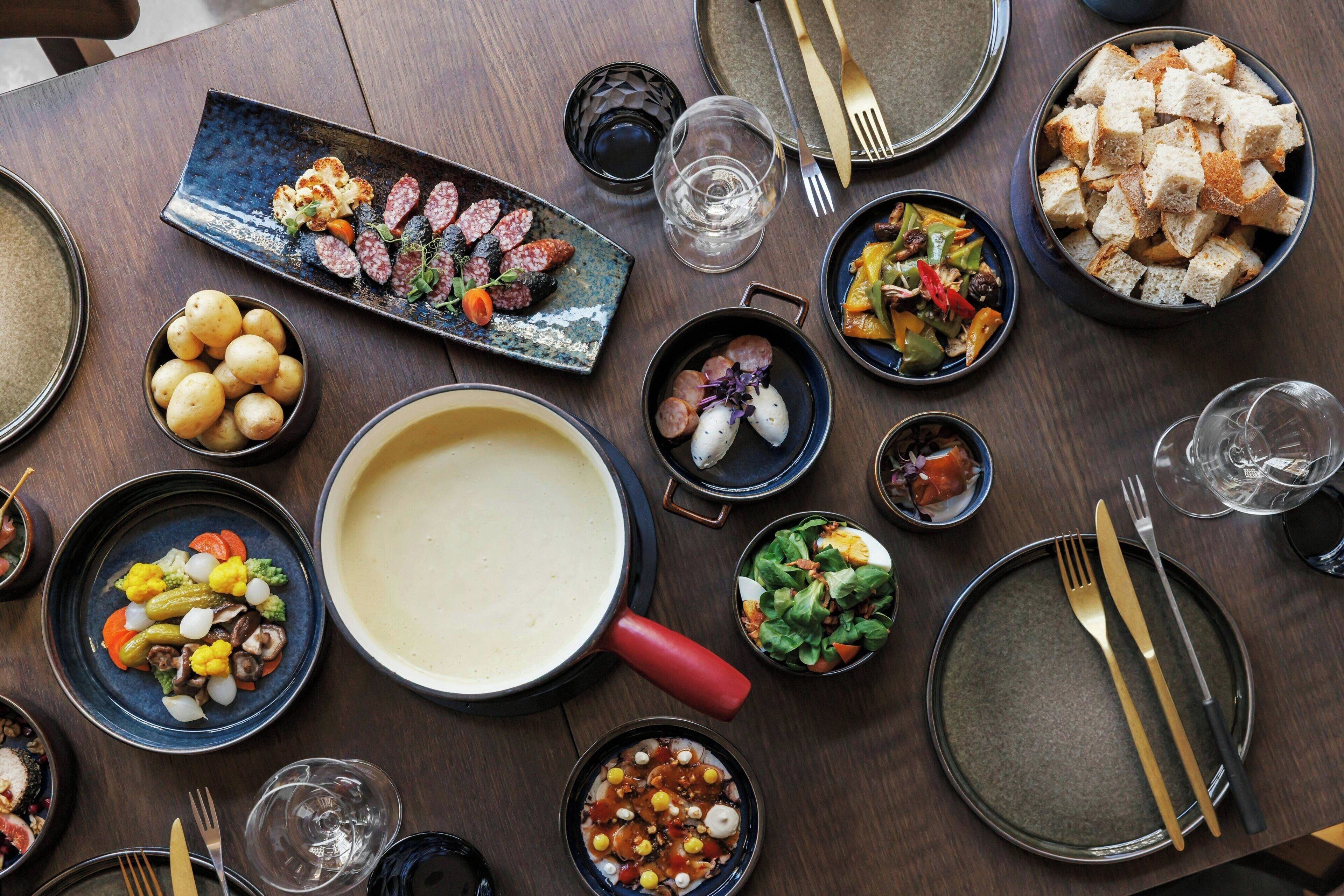 A dining table with various dishes, including a large pot, bowls of food, and cutlery.