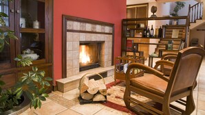 A cozy living room with a fireplace, wooden furniture, and a bookshelf.