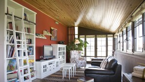 A living room with a bookshelf, a television, a sofa, and a window with curtains.