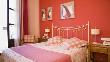 A bedroom with a bed, two bedside tables, a chair, and a window with curtains.