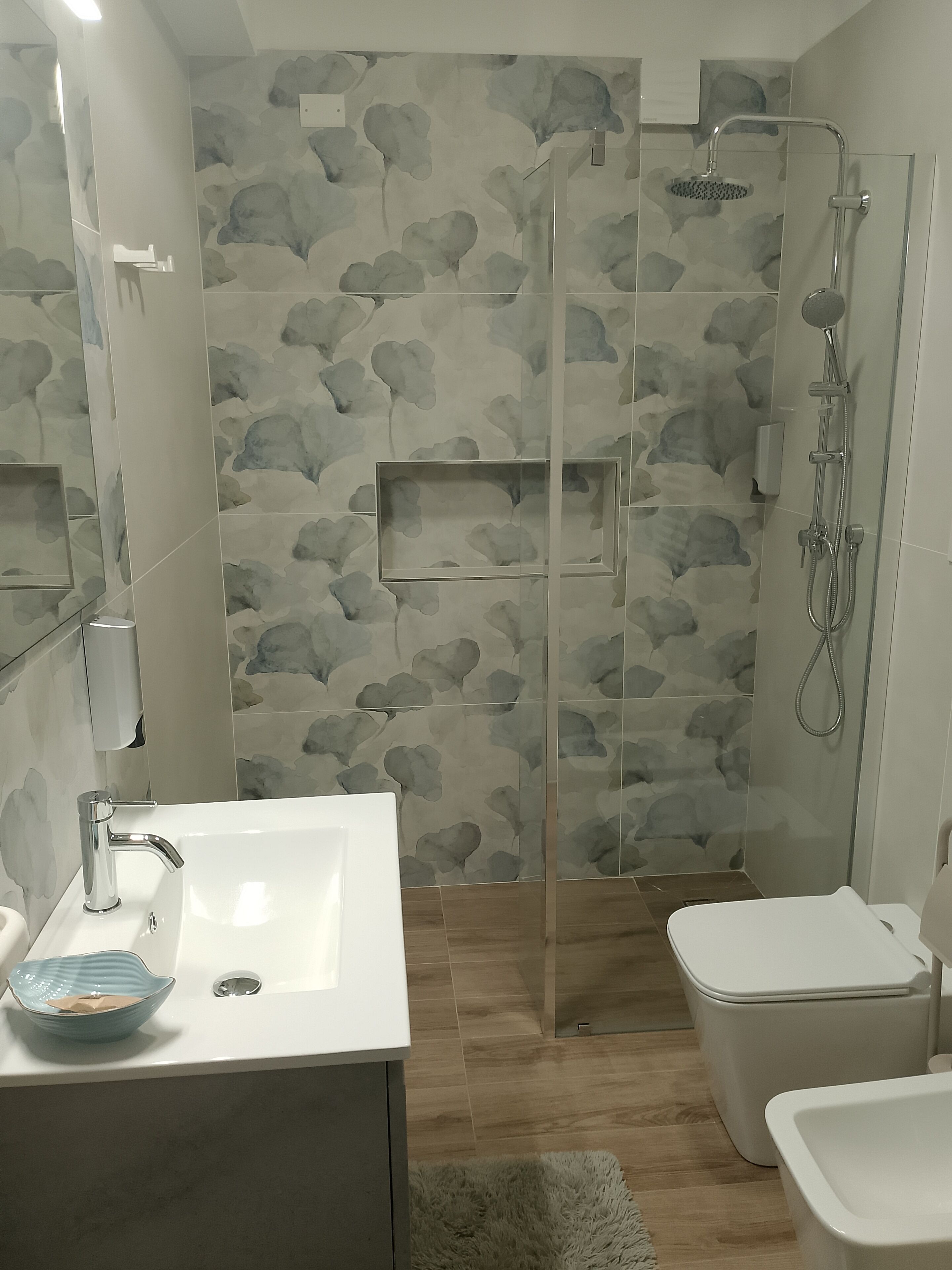 Un baño con ducha, inodoro, lavabo y espejo.