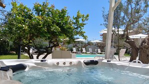 Un jacuzzi con vista despejada al área de la piscina, rodeado de sillones y sombrillas.