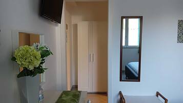 A hotel room with a dining table, a TV mounted on the wall, a mirror, and a bed.