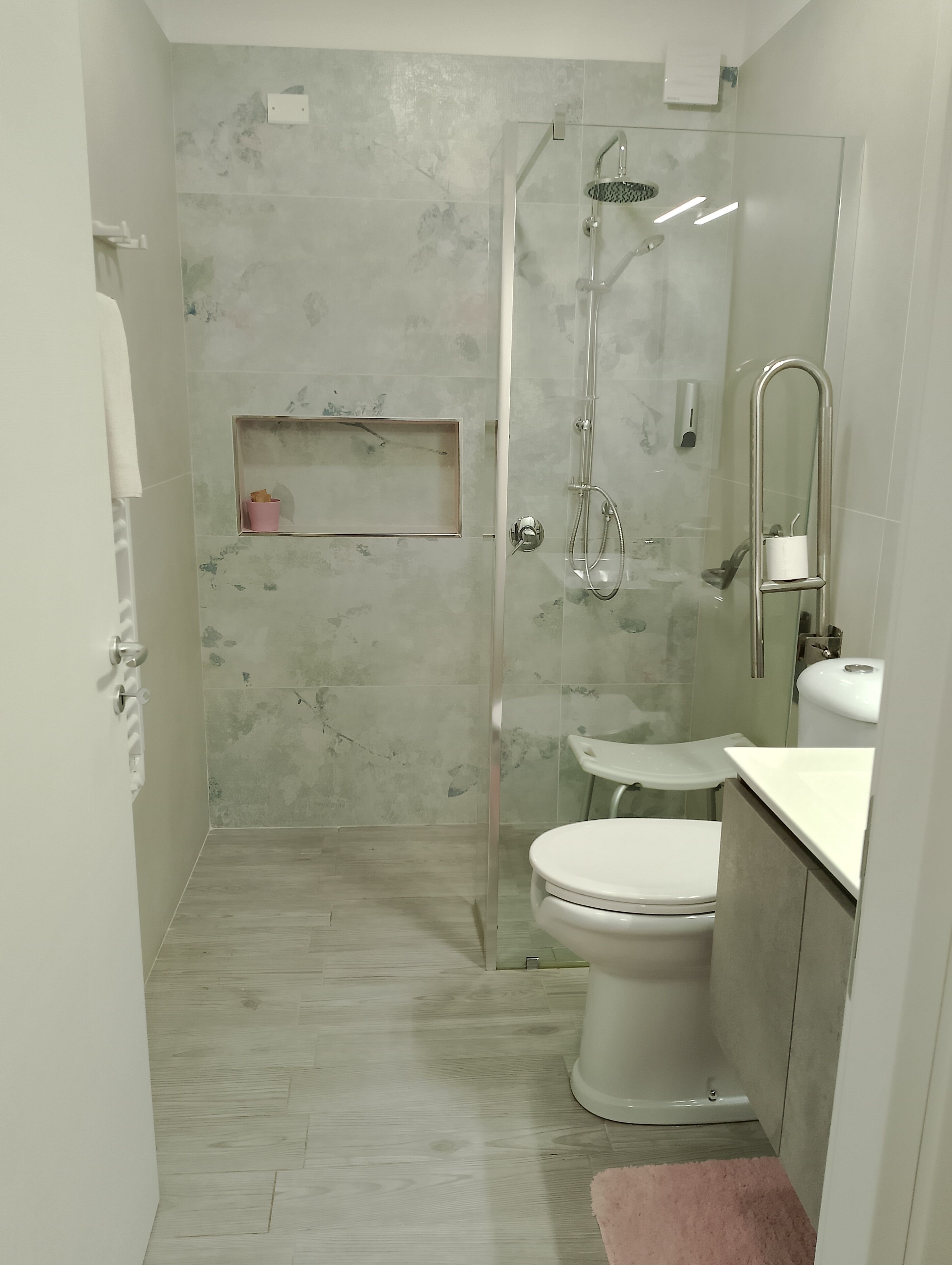 A modern bathroom with a glass-enclosed shower, a toilet, and a sink.