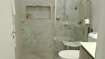 A modern bathroom with a glass-enclosed shower, a toilet, and a sink.