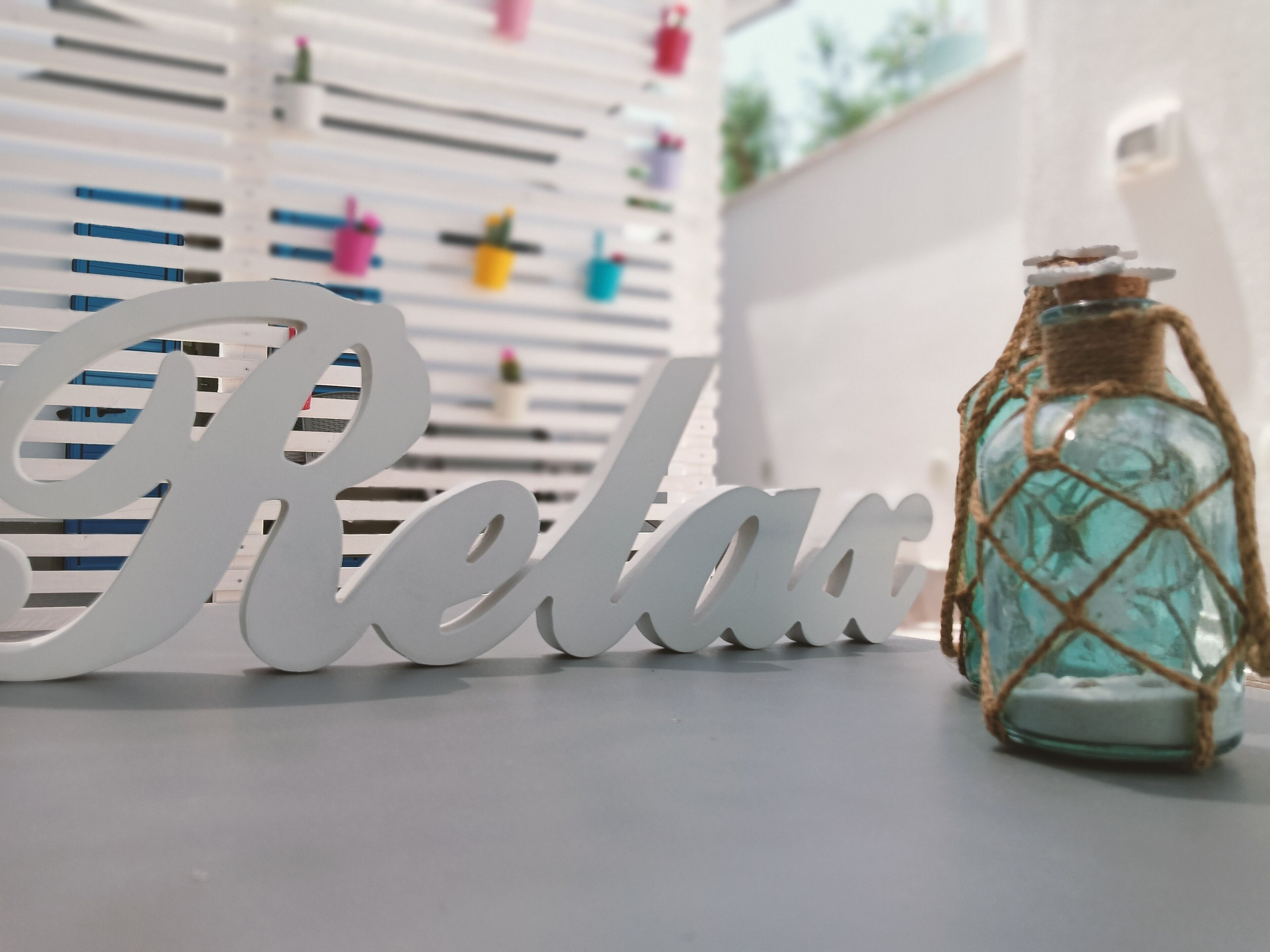 Een decoratief bord met de tekst 'Relax' en een klein flesje met een netje.