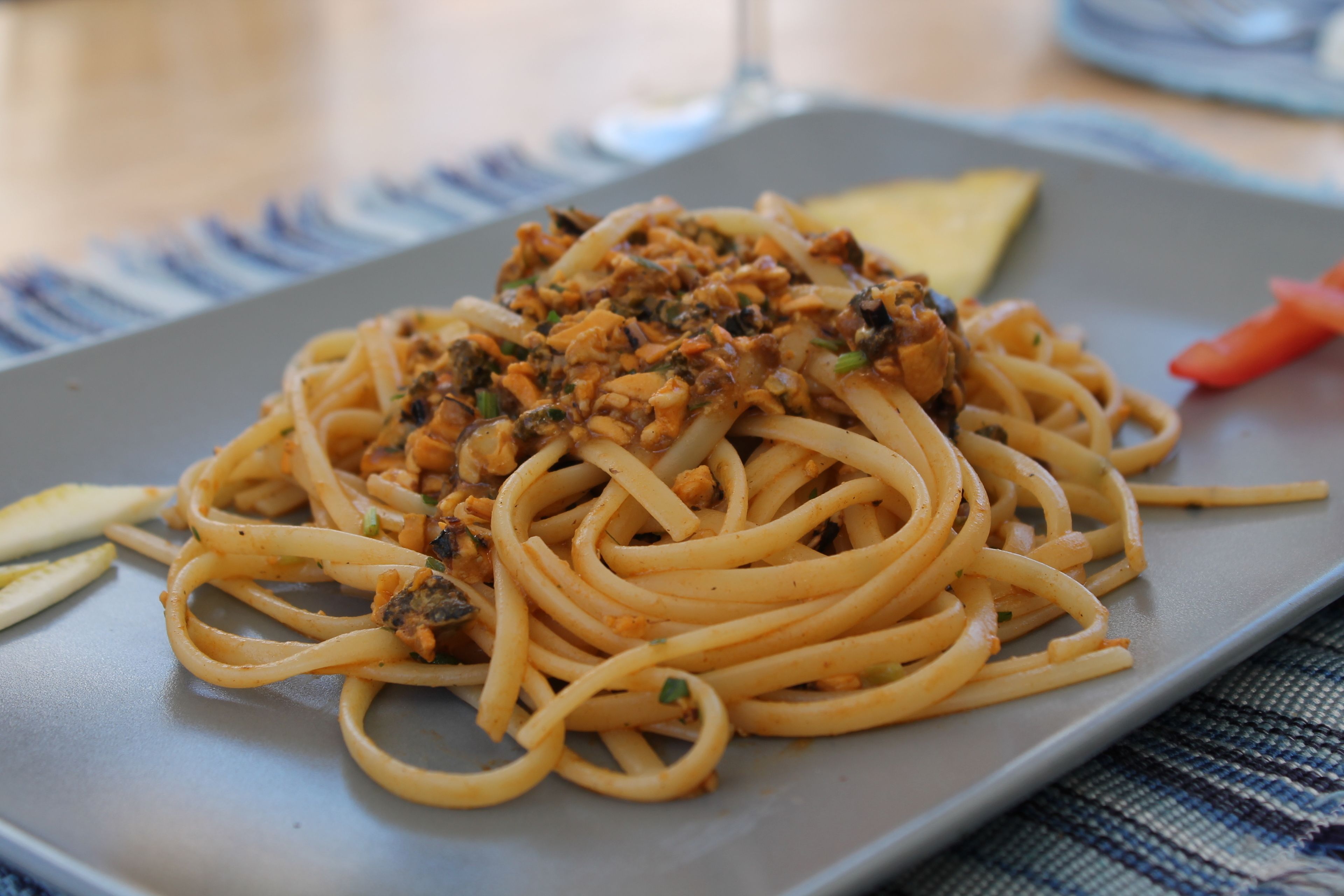 En portion spaghetti med en tomatsås och kött, serverad på en rektangulär tallrik.