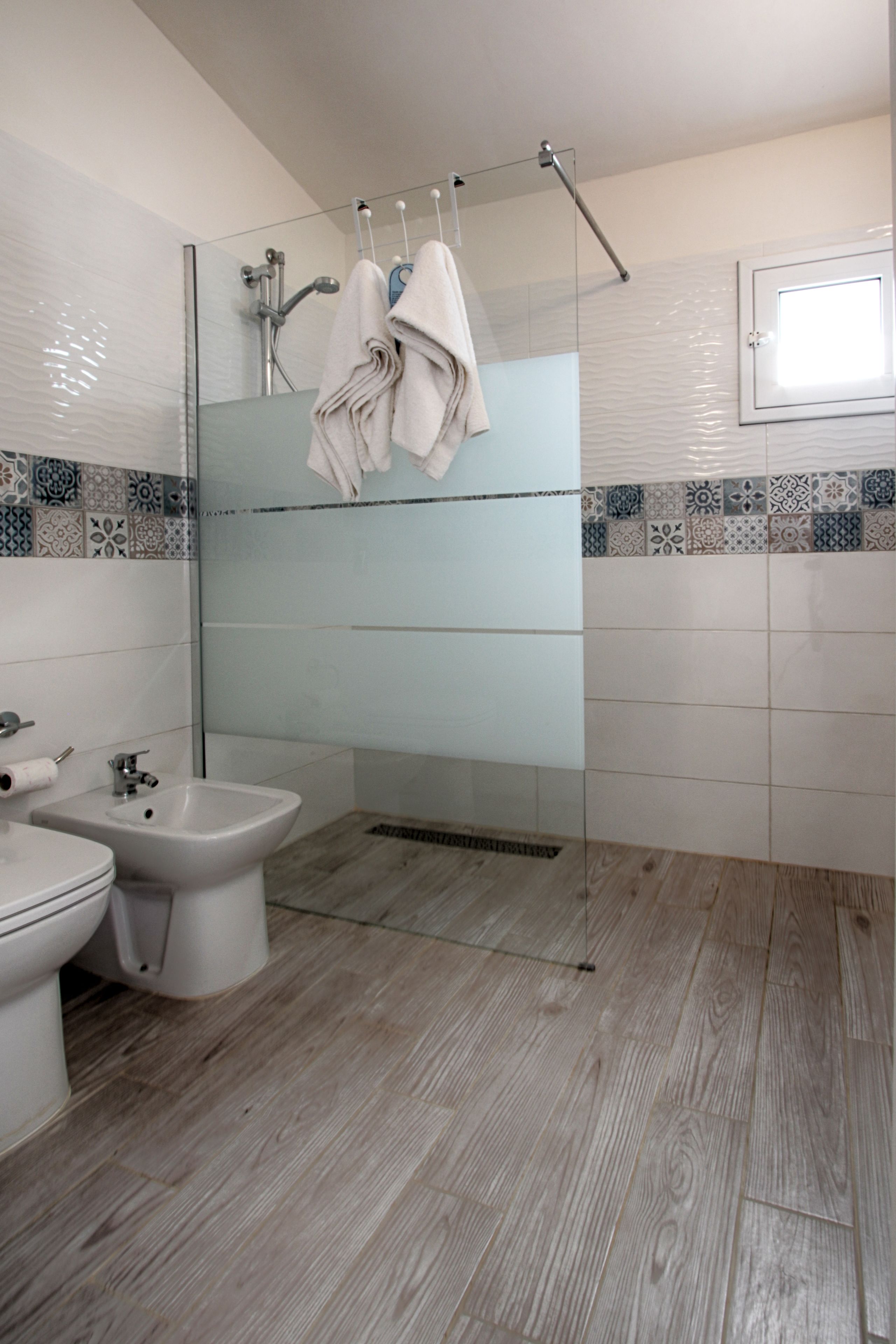 Ein Badezimmer mit Bidet, Toilette und einer Duschkabine aus Glas.