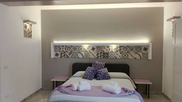 Een moderne slaapkamer met een bed, twee nachtkastjes, een wandlamp en een decoratieve wand van tegels.