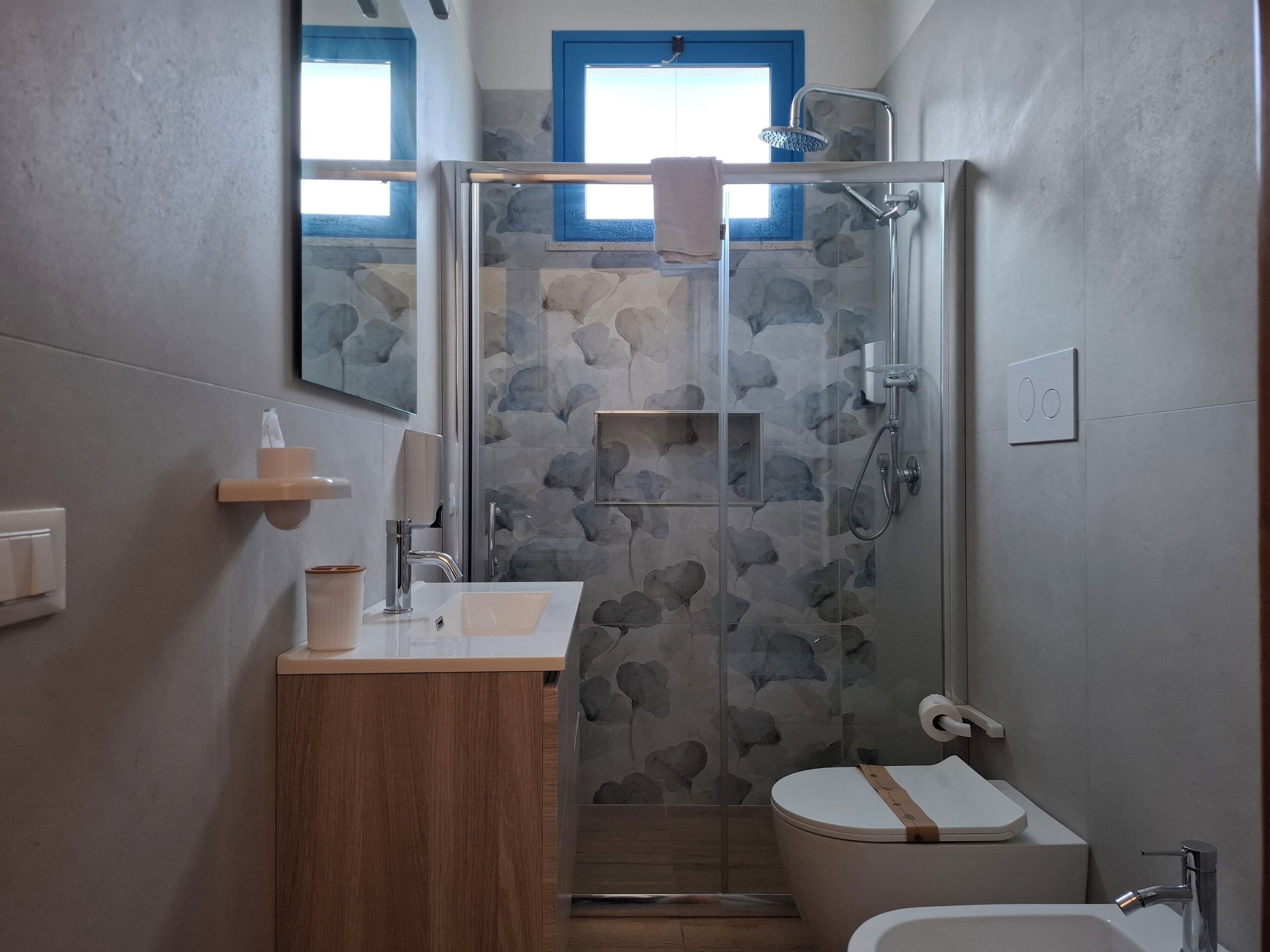 A modern bathroom with a glass-enclosed shower, a wooden vanity, a toilet, and a sink.