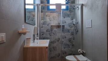 A modern bathroom with a glass-enclosed shower, a wooden vanity, a toilet, and a sink.