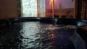 Un jacuzzi con agua, un banco de madera y una pared con diseño de hojas.