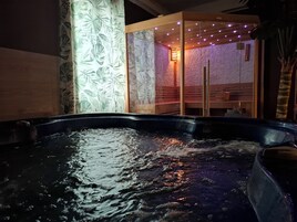 A hot tub with water, a wooden bench, and a wall with a leaf pattern.