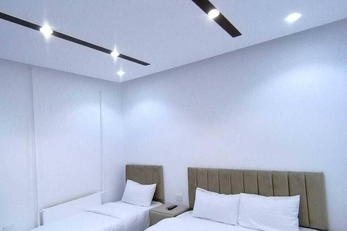 A modern hotel room with two beds, a neutral color scheme, and recessed ceiling lighting.
