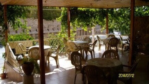 An outdoor patio with wooden tables and chairs, surrounded by greenery and stone walls. - Mussa Spring Hotel (Wadi Musa)
