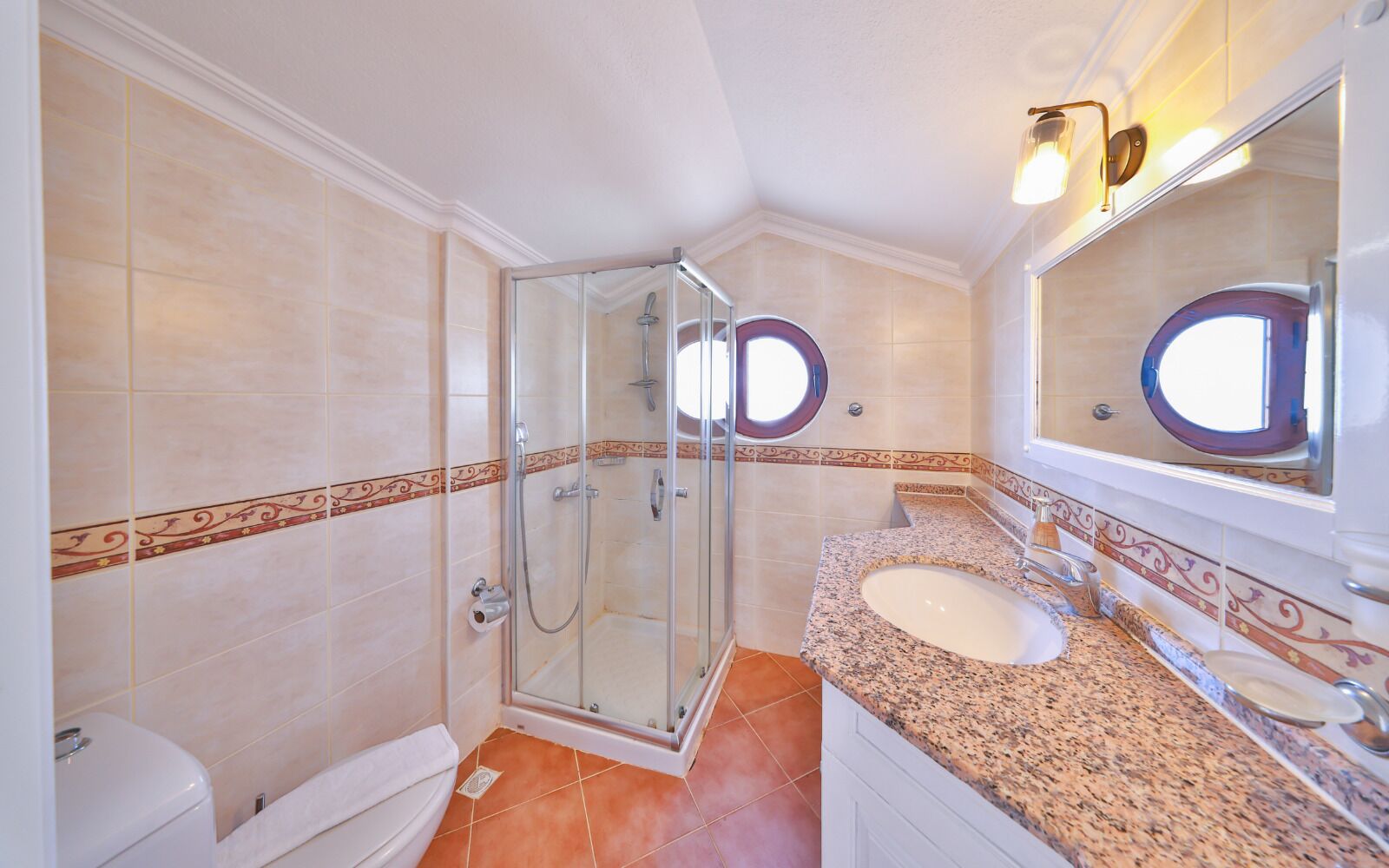A bathroom with a glass-enclosed shower, a white toilet, and a granite countertop with a sink.