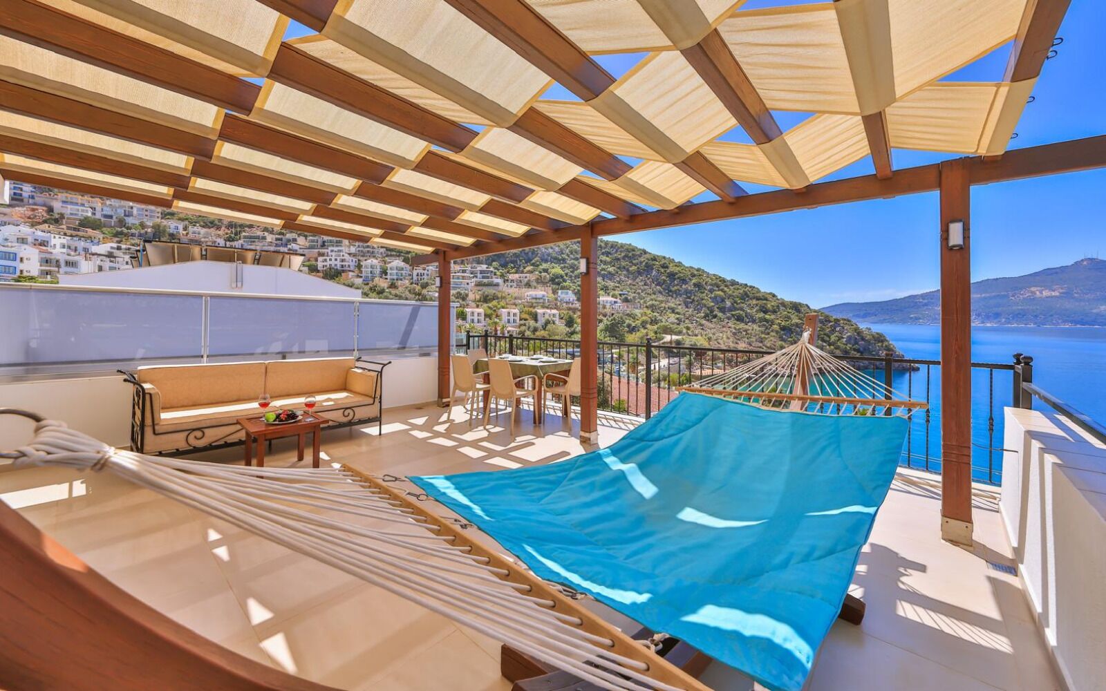 A balcony with a hammock, a sofa, and a table with a drink.