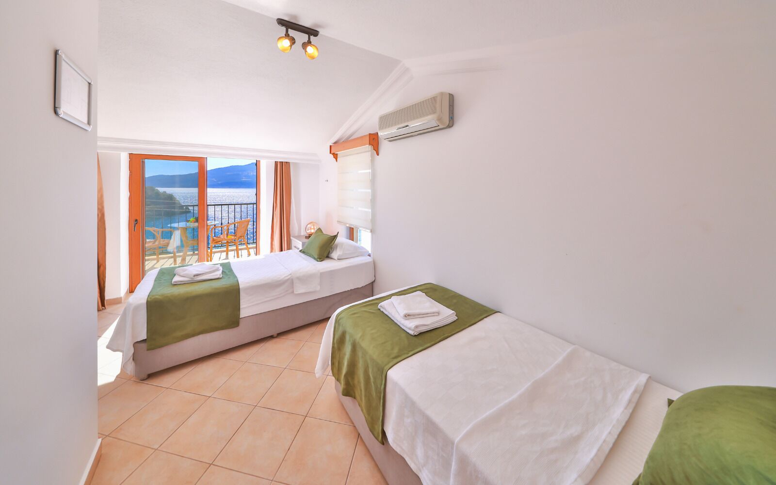 A hotel room with two beds, a balcony with a view, and an air conditioning unit.
