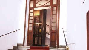 Una escalera con peldaños alfombrados de rojo que conducen a una puerta de madera.