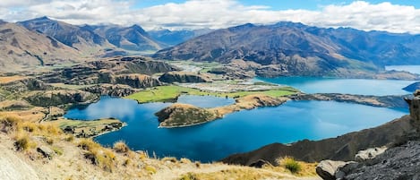 A mountainous landscape with a large lake surrounded by rugged terrain and distant peaks.