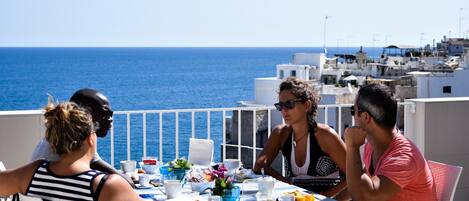 A group of people dining at a table with a view of the sea.