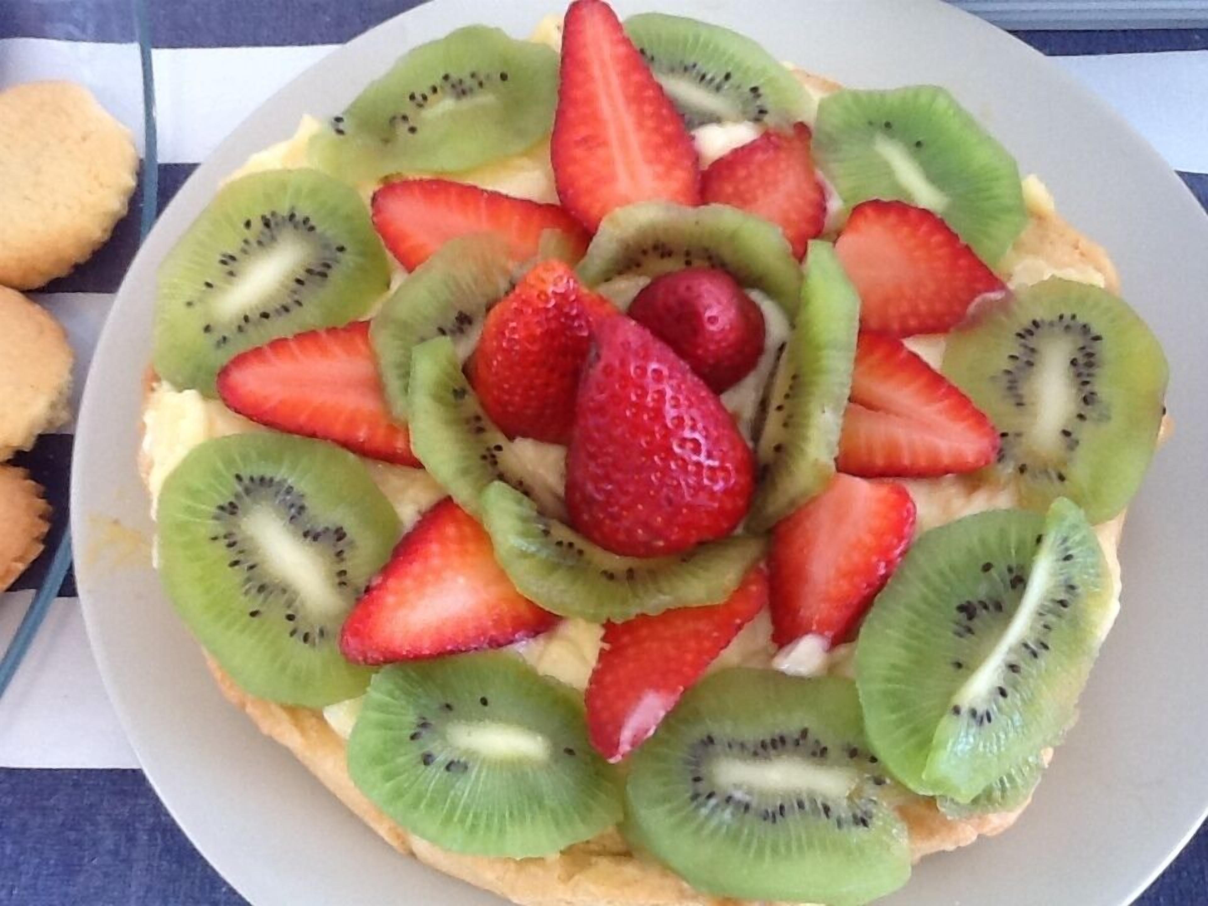Ein runder Kuchen mit Scheiben Erdbeeren und Kiwis.