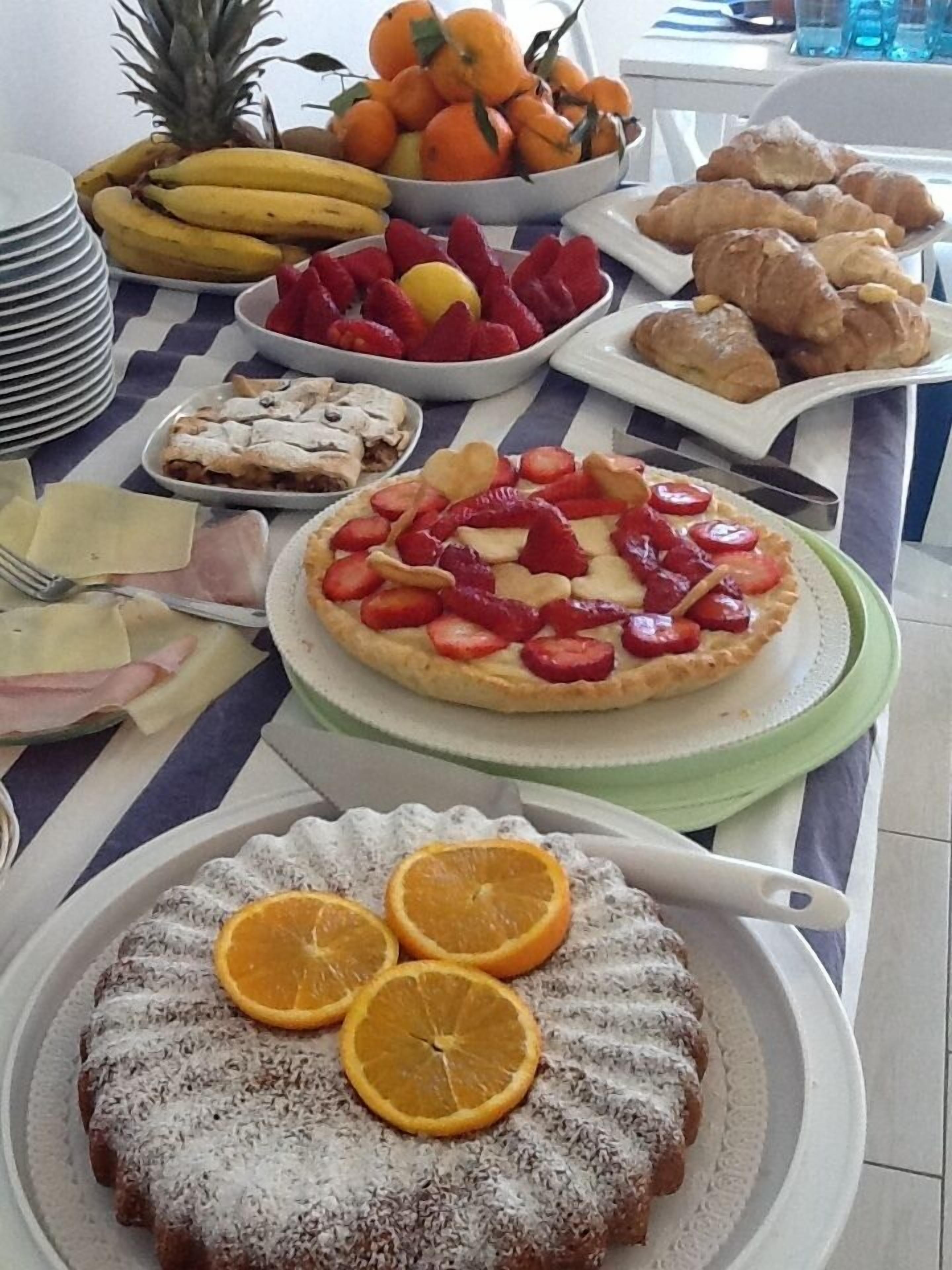 Een ontbijtbuffet met diverse gerechten, waaronder fruit, gebak en een taart.