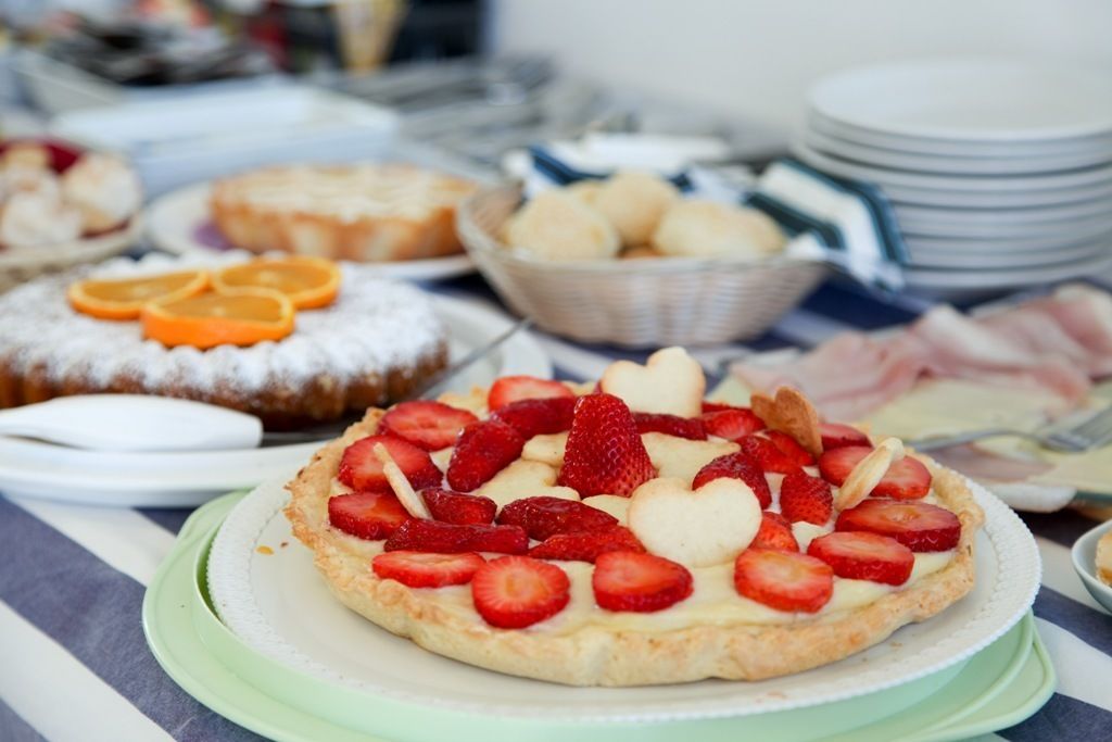 A dessert table with various pastries and a strawberry tart.