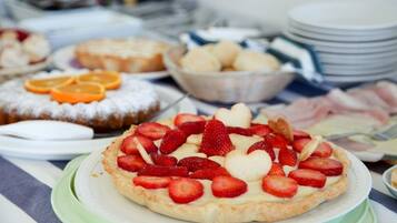A dessert table with various pastries and a strawberry tart.