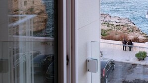 Vista desde un balcón sobre una zona costera con edificios y cielo despejado.