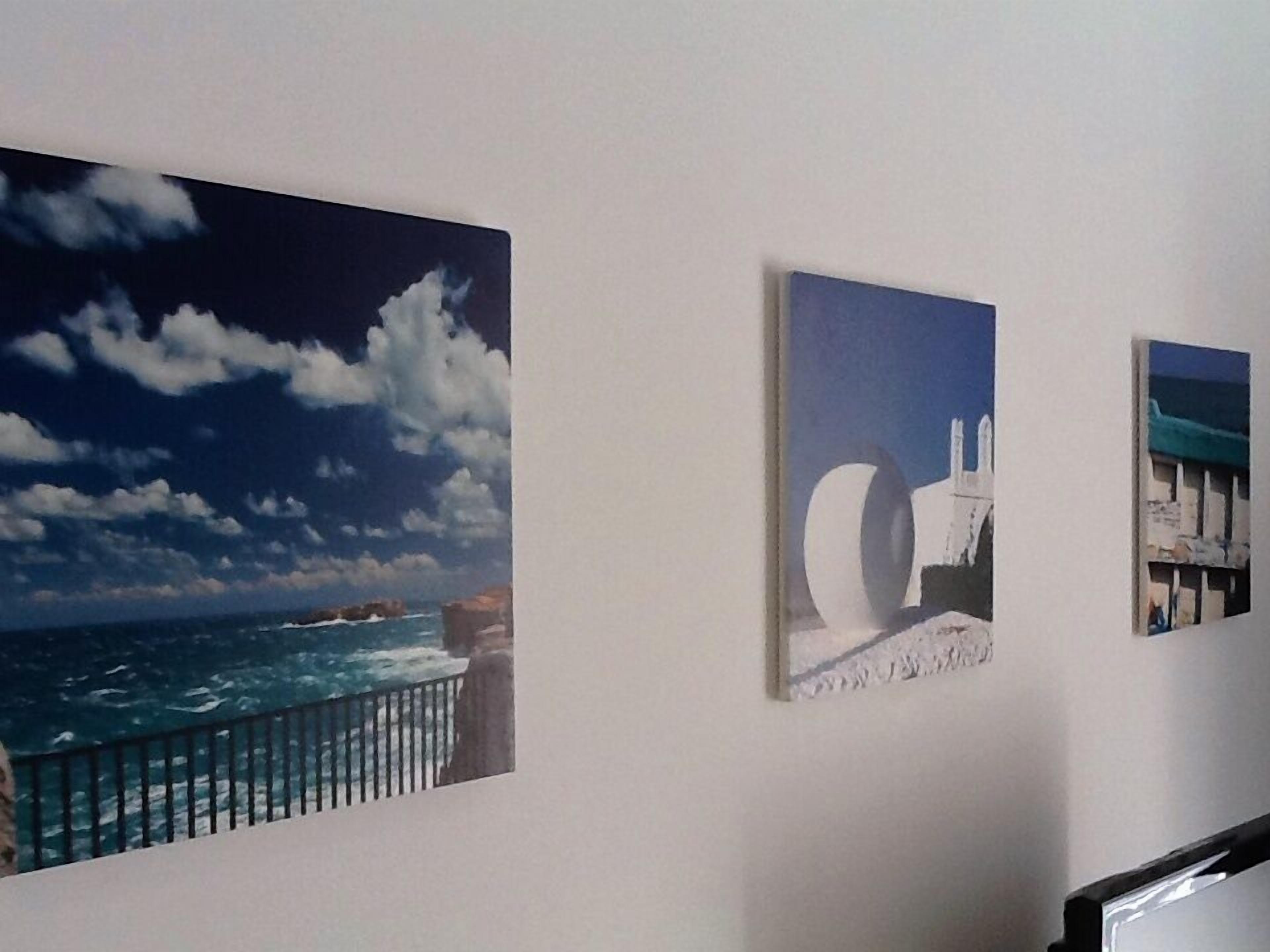 A wall with three paintings depicting coastal scenes.
