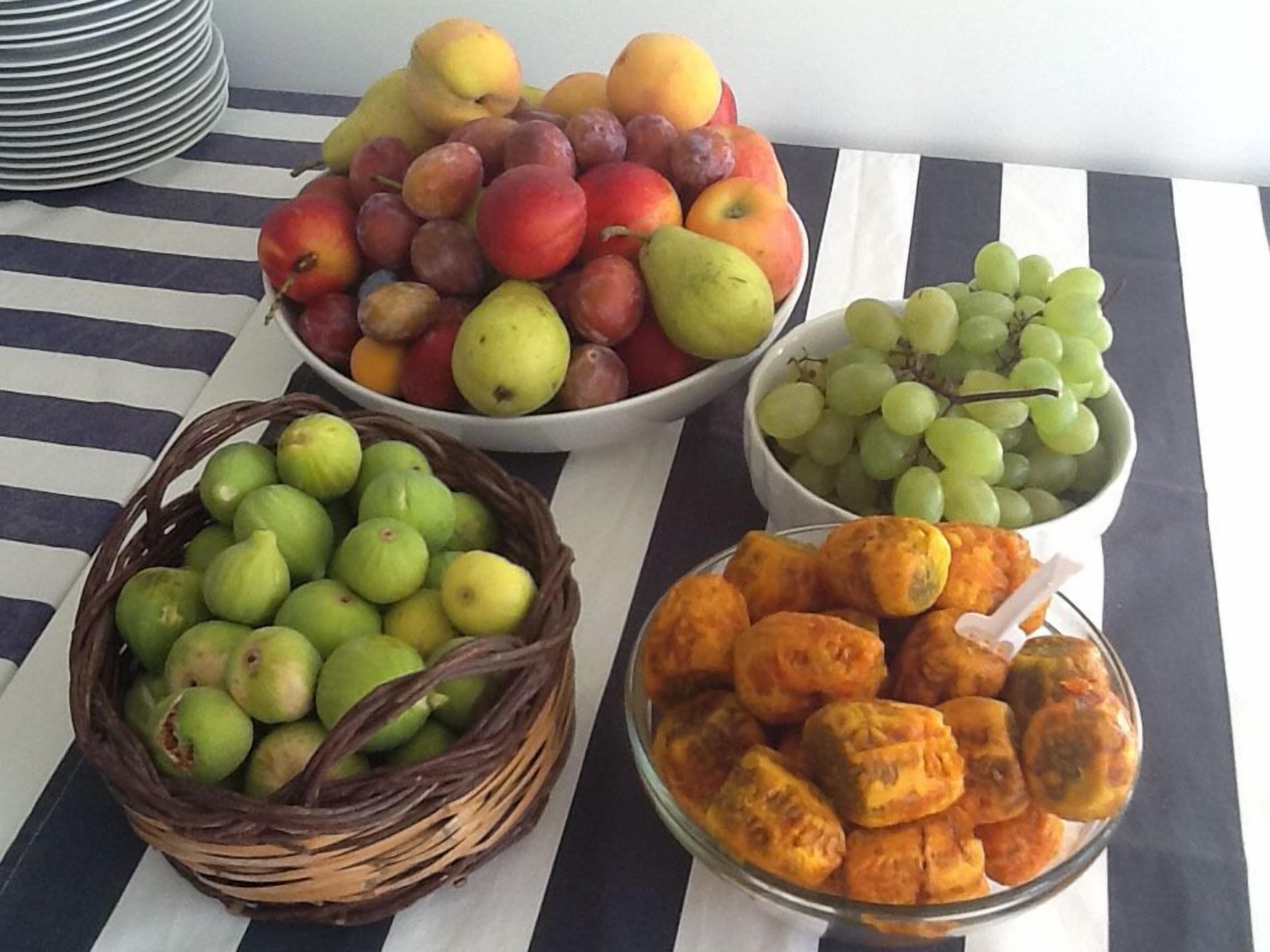 A table with various fruits and a basket of green apples.