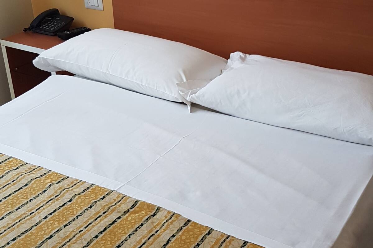 Ein Hotelzimmer mit einem Bett, einem Telefon und einer Wandlampe.